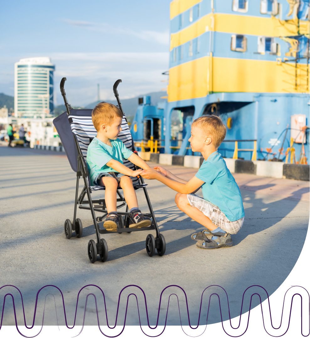 Dois meninos brincando com um carrinho de bebê no parque.