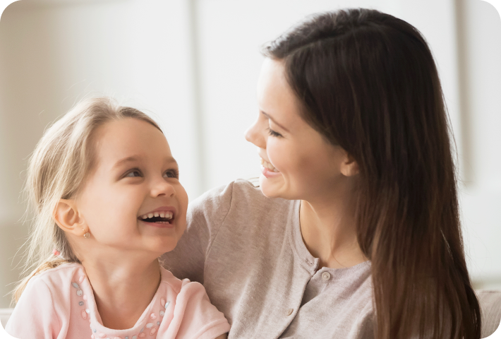 Mãe e filha sorrindo uma para a outra.