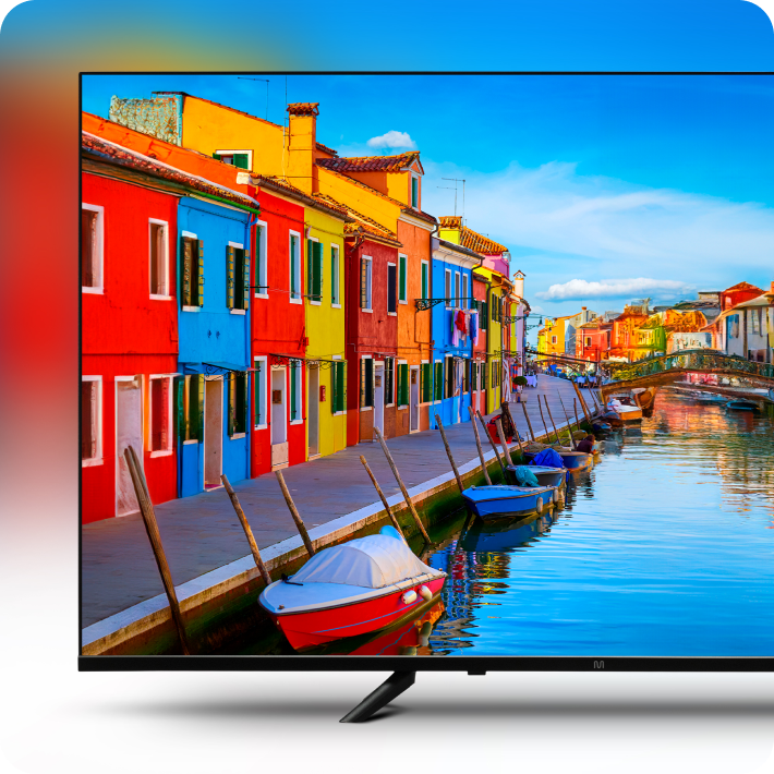 Imagem de uma TV transmitindo uma cena com casas coloridas ao fundo bem ao lado de um canal, onde há pequenas embarcaçoes paradas.