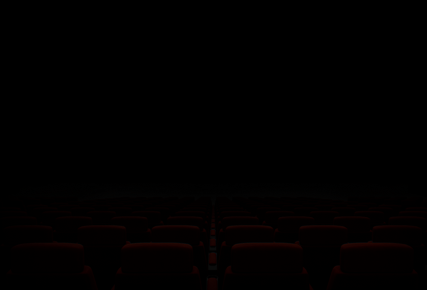 Sala de cinema com assentos vermelhos e uma tela grande.