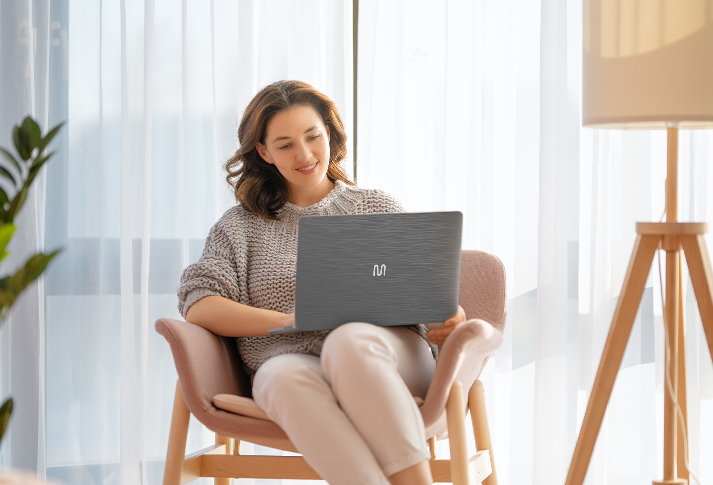 Uma mulher de óculos está sentada em uma mesa com um laptop.