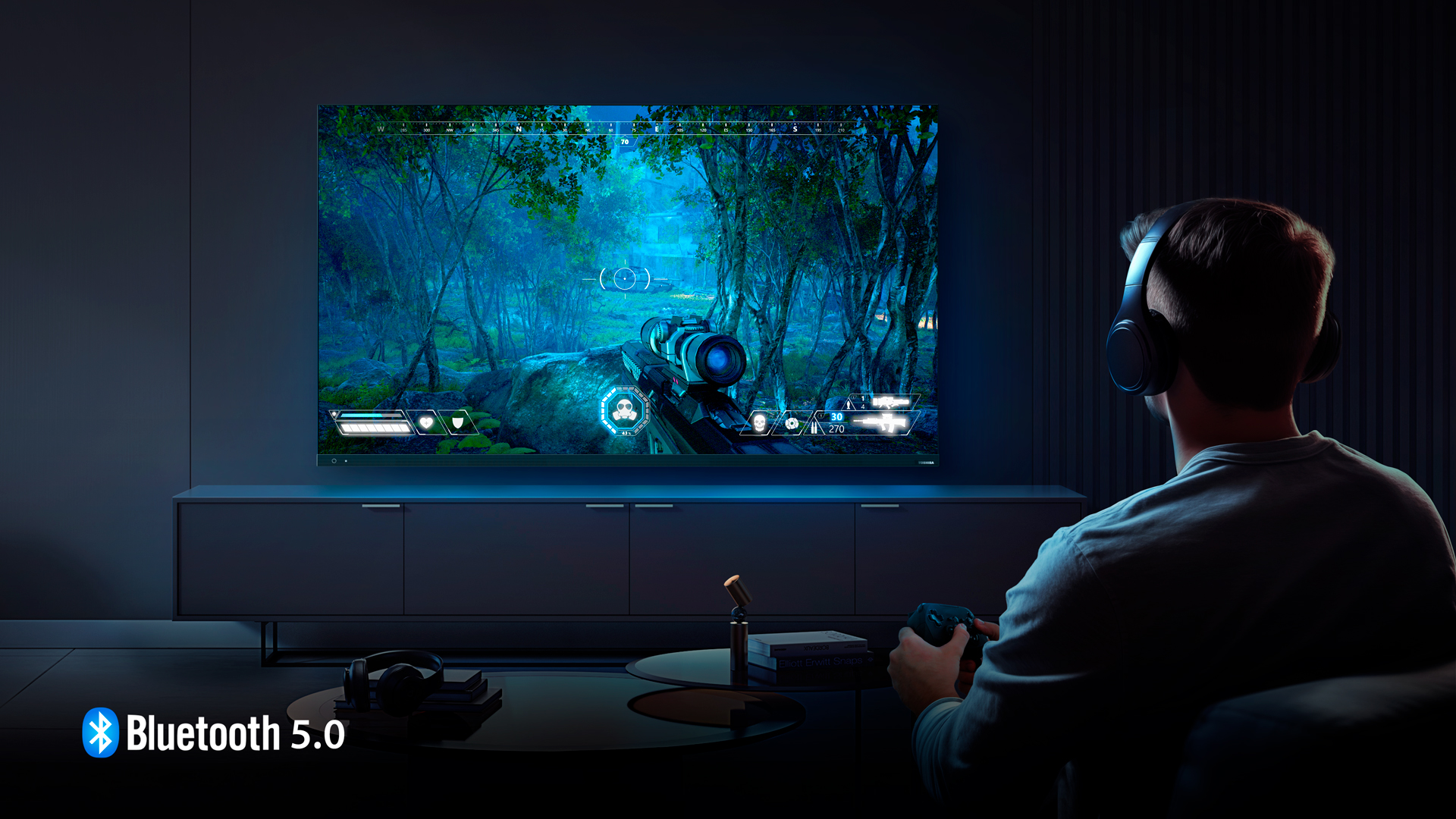  Imagem de um homem jogando videogame em uma TV, evidenciando o recurso Bluetooth 5.0