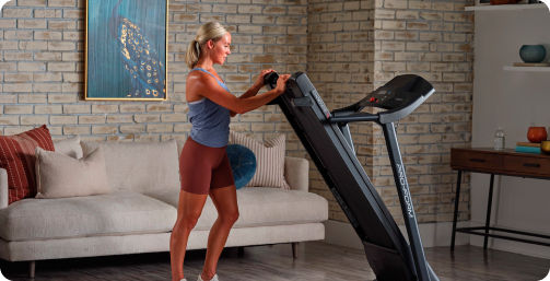 Mulher levantando a esteira ProForm Cadence 4.0 em sua sala de estar.