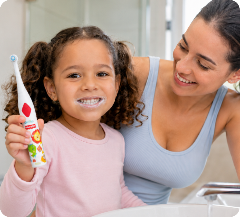 Menina escovando os dentes acompanhada pela mãe